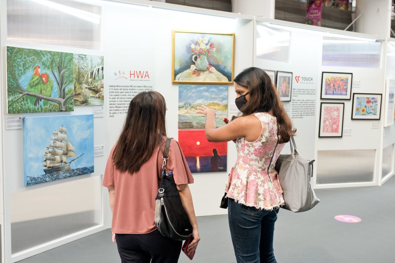 two women standing in front of a exhibition panel